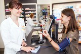 Eine junge Frau, die sich in einer Apotheke den Blutdruck messen l�sst