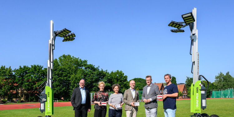 Auf dem Bild sind mehrere Personen zu sehen. Diese stehen auf einem Rasenplatz,